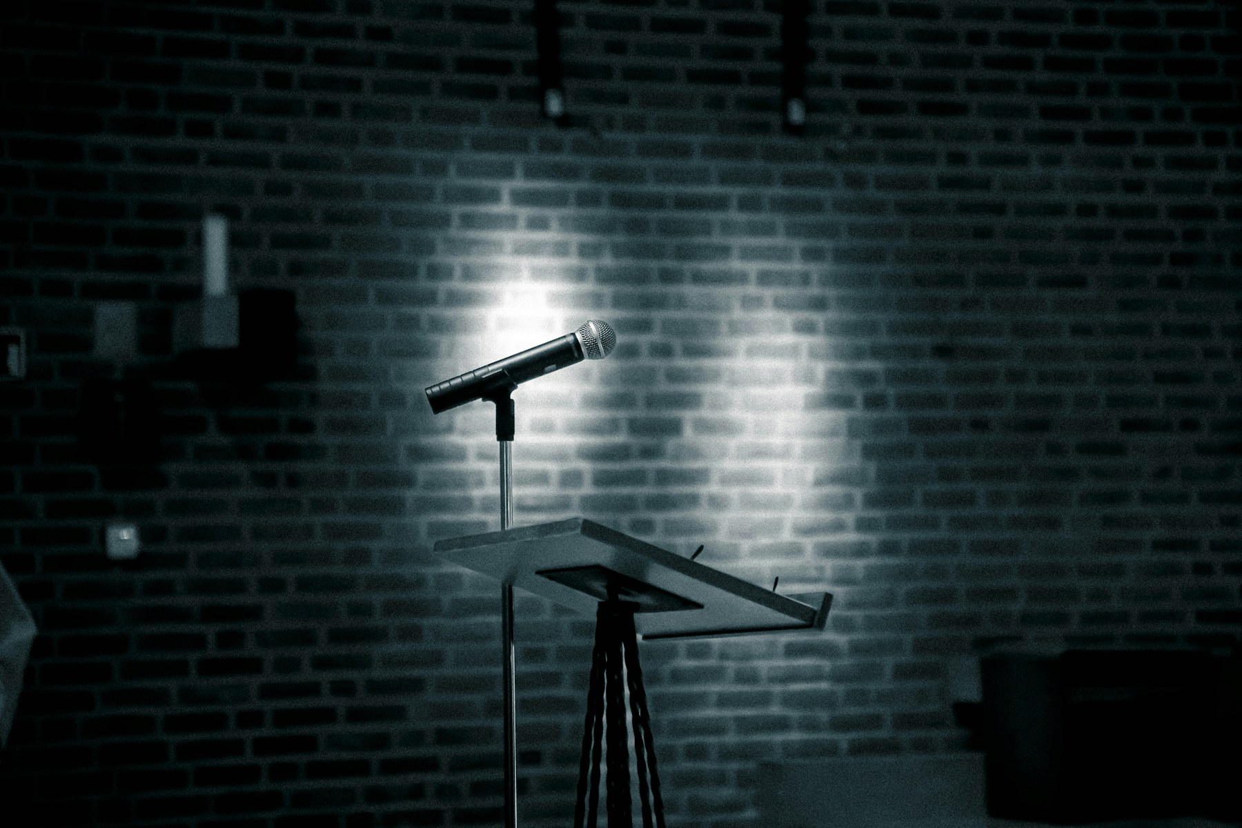 A microphone waiting on a brick-wall stage